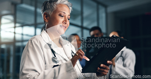 Image of Doctor, mature woman and happy with tablet in night, typing or smile for results, meme or notification in hospital. Senior nurse, digital touchscreen or funny video with click, scroll or social media