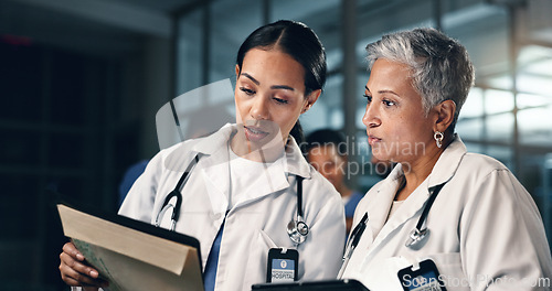 Image of Doctor, women together and tablet in night, documents or analysis for results, decision or info in hospital. Mature medic, partnership and paperwork for healthcare, wellness and planning with choice