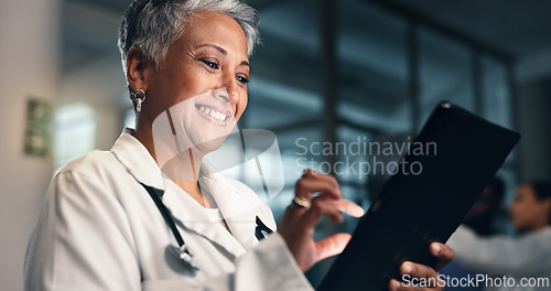 Image of Doctor, mature woman and happy with tablet in night, typing or smile for results, meme or notification in hospital. Senior nurse, digital touchscreen or funny video with click, scroll or social media