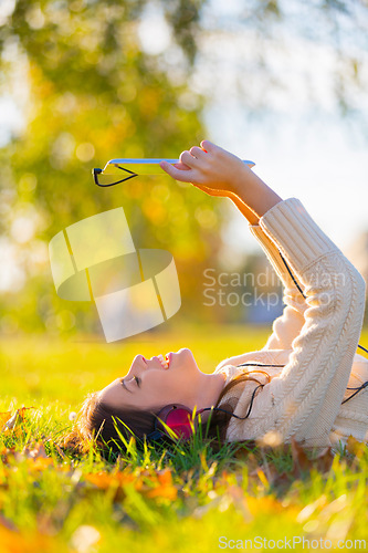 Image of Woman, headphones and tablet for music on grass, streaming radio and podcast outdoors. Female person, nature and internet for movie subscription on weekend, calm and peaceful playlist on lawn