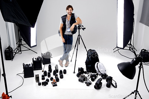 Image of Portrait, smile and man with gear, photography and equipment in a work studio with confidence. Person, photographer and entrepreneur with tools or lights with startup and freelancer with professional