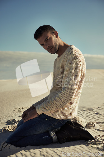 Image of Man, fashion and portrait in desert, style and sun for Dubai travel and vacation while kneeling. Male person, modern and sand dunes on holiday, trip and cool confidence outdoor in nature in Abu Dhabi