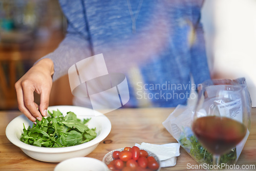 Image of Person, cooking and prepare salad on table in kitchen closeup with wine in home for dinner. Tomato, lettuce and hands with healthy food in bowl to meal prep on counter for nutrition and diet in house