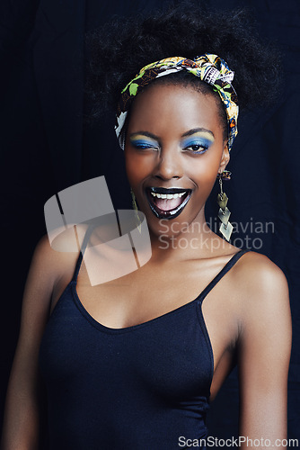 Image of African woman, wink and studio for makeup, style and smile for eye shadow and glamour. Black female model, dark background and cosmetic, portrait and face for cultural, fashion and elegant earrings