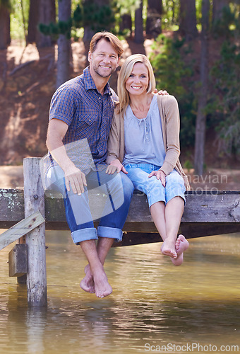 Image of Mature couple, lake and sitting on dock, countryside and commitment with love in marriage. Happiness, smile and hug by partner, family and woman with man vacation for sightseeing in nature to relax