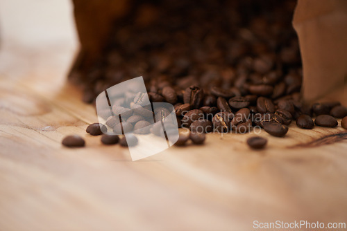 Image of Table, closeup and fresh roasted coffee beans, spilling from a paper bag onto a vintage wood counter with copy space. Studio, aromatic bitter caffeine to feel refreshed with hot, refreshing beverage