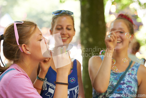 Image of Park, friends and women with bubbles in nature on holiday, vacation and weekend outdoors. Happy, smile and people blowing soap bubble for bonding, fun and relax together on adventure, travel and trip