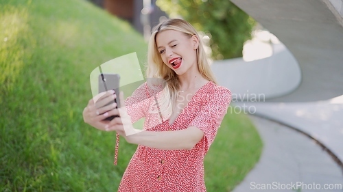 Image of Young Woman in Red Dress Using Smartphone Outdoors