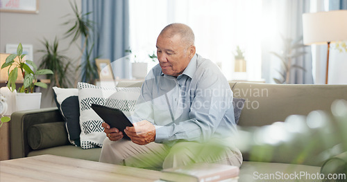 Image of Tablet, home and senior man on sofa, reading email or ebook in living room to relax. Retirement, technology and elderly person in lounge for crossword puzzle, news and information on internet app