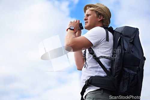 Image of Man, tourist and binoculars with backpack for hiking, sightseeing or outdoor travel with blue sky background. Male person or young traveler with bag or optical instrument for view, vision or scope