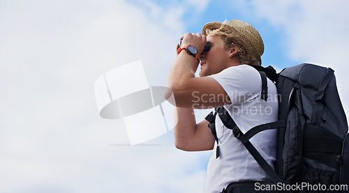 Image of Man, hiker and binoculars with backpack for hiking, sightseeing or outdoor travel with blue sky background. Male person, traveler or tourist with bag or optical instrument for view, vision or scope