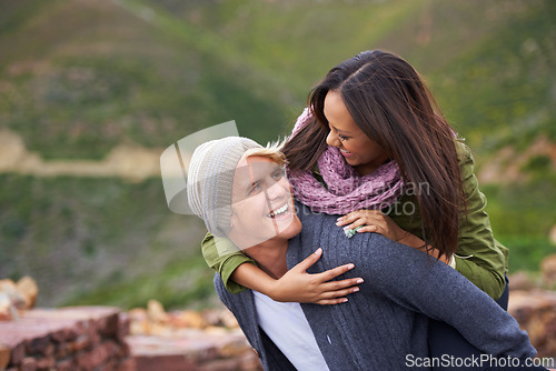 Image of Happy, couple and piggyback in nature, hiking and travel together on adventure for date on holiday. Funny, outdoor and man carrying woman, trekking and interracial people laughing in the countryside