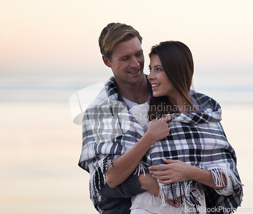 Image of Couple, hug and sunset at beach with blanket for vacation, love and care in nature, outdoor and ocean. Man, woman and embrace with smile, bonding and happy for memory on holiday by sea in Australia