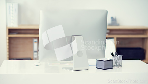 Image of Modern, office and computer in workspace on desk with stationery, pens and sticky notes on table. Technology, furniture and back view of monitor in empty, comfortable and interior of workplace