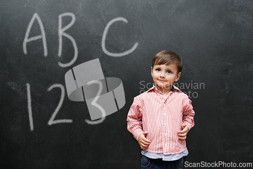 Image of Child, boy and face with smile by blackboard with letters, numbers and happiness in classroom at school. Kid, student and happy for knowledge, learning and chalkboard with math, alphabet or preschool