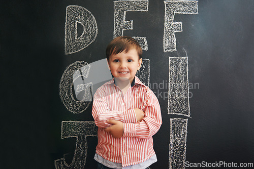 Image of Child, boy and portrait with smile by blackboard with letters, alphabet or drawing in classroom at school. Kid, student and happy for knowledge, learning and chalkboard with illustration or preschool