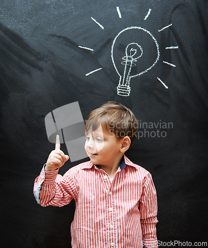 Image of Child, solution and lightbulb on chalkboard for ideas, learning and education in school with answer or questions. Happy kid, student or boy with light bulb, emoji and creative knowledge on blackboard