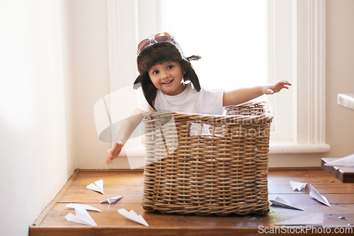Image of Flying, fun and child with paper plane, fantasy, and imagination playing in basket in home. Adventure, little pilot and playful boy in box with future dream, growth and development with airplane.