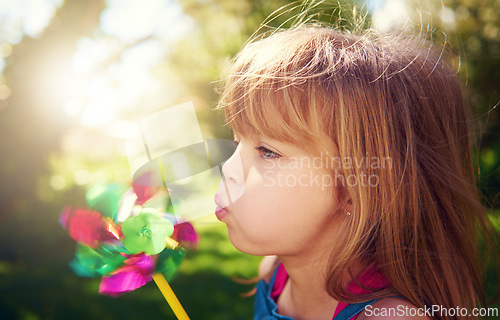 Image of Young girl, outside and pinwheel in garden, fun and enjoy freedom of outdoor and profile. Child, backyard and summer for playing, toy and windmill for nature vacation or holidays and happiness