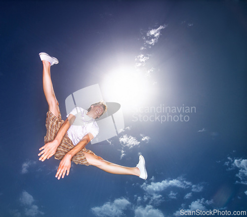 Image of Boy, blue sky and jump outdoor with low angle, energy and lens flare of sunshine. Young teenager, below and leap in air by clouds in summer, moving and kid screaming for freedom with agile action