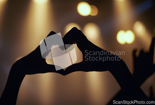 Image of Person, hands and music concert with heart shape enjoying and loving the performance. Close up a finger sign during a live showing the music band on stage with support while partying with silhouette