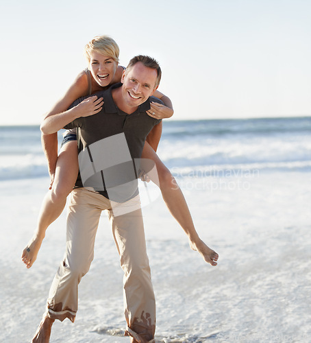 Image of Couple, portrait and happy on beach with piggyback for bonding, honeymoon date and weekend holiday. Face, man and woman with embrace, smile and love in water by sea for vacation, travel and adventure
