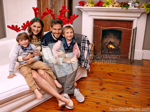 Image of Christmas, portrait and happy family on sofa in home for holiday or festive celebration. Xmas, parents and smile of children in living room with antlers, bonding and kids together at party in house