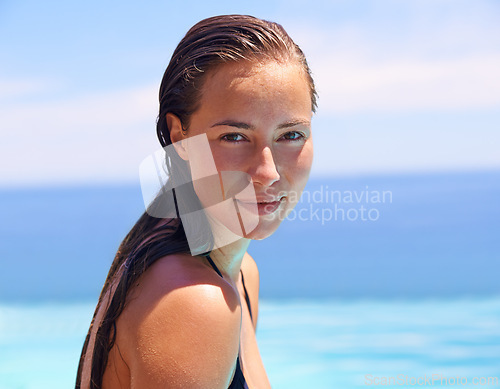 Image of Portrait, summer and swimming pool with woman tourist outdoor for holiday or vacation to relax on blue sky. Face, travel and wet with confident young swimmer person in water for resort getaway