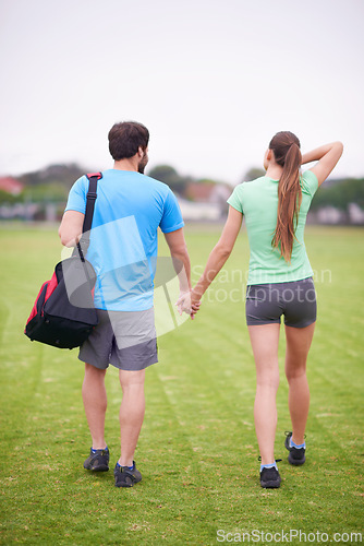 Image of Couple, holding hands and back in park for workout, walking or training for wellness with bag in summer. People, man and woman for support, care or bonding on lawn for exercise for fitness in England