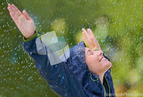 Image of Woman, rain and freedom with a smile from wet climate, water and weather outdoor in a park. Happy, relax and female person with jacket for cold on holiday travel and vacation with raincoat and joy