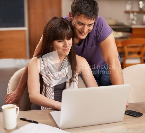 Image of Couple, happy and laptop in kitchen with paper for budget, smile and coffee on table by pen. Partners, love and payment of apartment rent with technology, tax and online with connection from internet