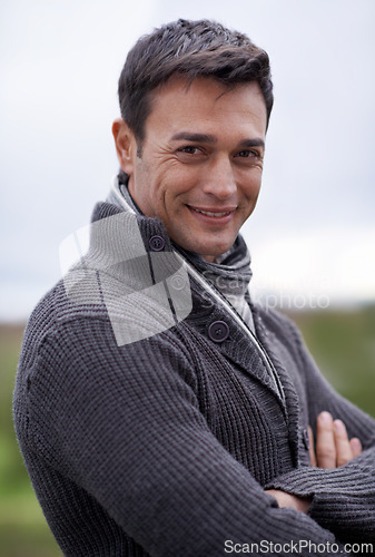 Image of Man, portrait and smile with arms crossed or sky for relax, travel and winter adventure on holiday or vacation. Person, tourist and face or happiness in nature or outdoor for fresh air and wellness