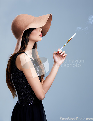 Image of Glamour, profile and woman in hat with cigarette, confidence and vintage fashion in studio. Classic, chic and elegant style with girl smoking on grey background in designer clothes with aesthetic.