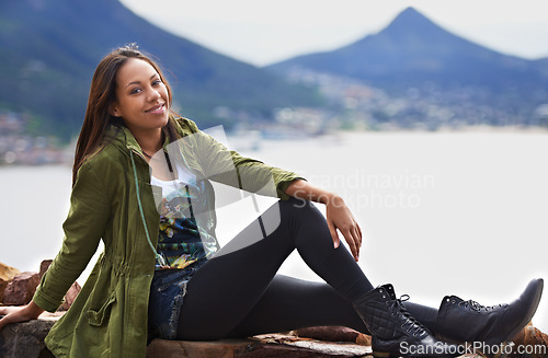 Image of Portrait, woman and smile for sitting with mountain and sea on vacation, holiday or roadtrip. Female person, tourist or traveler with calm, joy and happiness while relaxing in Cape Town, South Africa