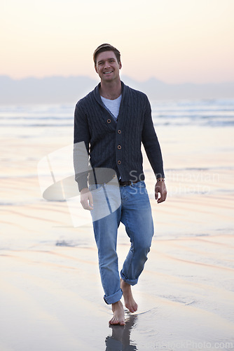 Image of Man, walking and happy in portrait by ocean, sunset and vacation with nature to relax at beach. Person, travel and outdoor by sea with feet in sand for holiday, adventure or smile by sea in Australia