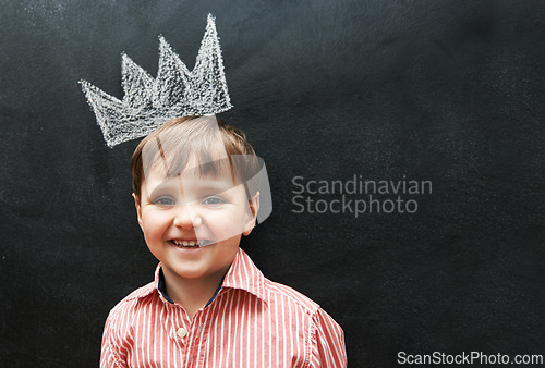 Image of Boy, portrait and crown on chalkboard with smile from cute learner in preschool. Young student, happy and learning in classroom for education in art for development of creativity for youth