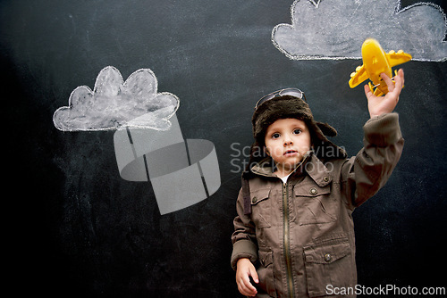 Image of Child, boy and face by blackboard with plane for creative fun, playing or drawing of clouds for imagination. Student, kid and confidence with airplane, chalkboard or illustration for knowledge or sky