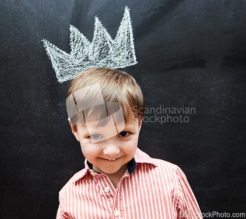 Image of Little child, portrait and crown on blackboard from mischief of drawing by cute boy in classroom. Young kid, creative and artistic in preschool for elementary education, youth and clever student