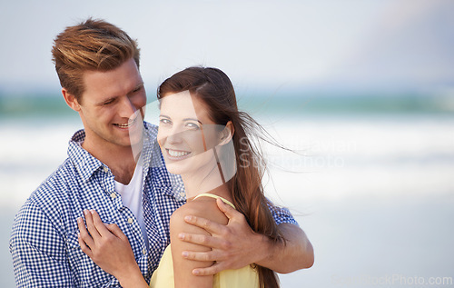 Image of Portrait, couple and smile for embrace, beach and romantic date on sunny afternoon in Spain. Hug, man and woman in love for kind relationship, fun dating and bonding together on weekend getaway