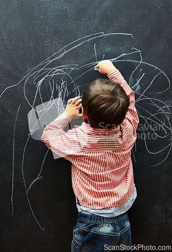 Image of Young child, scribble and art on chalkboard in classroom of preschool for education of little boy. Kid, drawing and creative on blackboard with illustration for elementary, student and sketch
