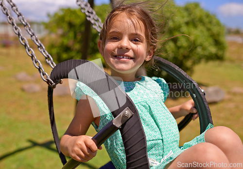 Image of Cheerful child, swing and playing at a playground with summer hobby for kids or kindergarten leisure activity. Portrait, little girl and outdoor in nature park for fun and happiness with a smile