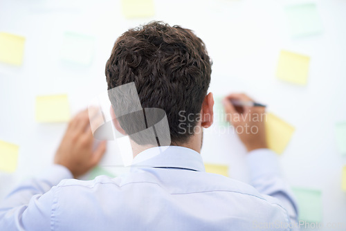 Image of Businessman, writing and sticky notes on wall for planning, brainstorming and project reminder with rear view. Entrepreneur, employee and ideas for agenda, schedule and proposal information at work