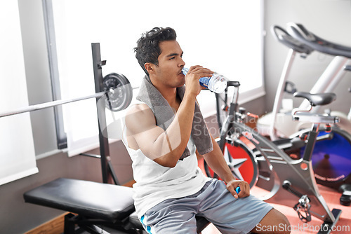 Image of Gym, fitness and man drinking water for training, wellness or exercise recovery, break or resting. Workout, hydration and thirsty male athlete with sports drink after intense, cardio or bodybuilding