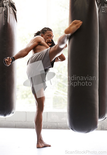 Image of Man, kick boxing and bag with exercise, foot and combat for training with balance, power and precision in gym. African athlete, person or fighter with workout, fitness or strike for challenge in dojo