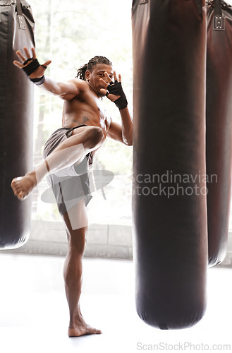 Image of Man, kick boxing and bag with training, foot and combat for exercise with balance, power and precision in gym. African athlete, person or fighter with workout, fitness or strike for challenge in dojo