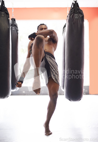 Image of Man, kick boxing and bag with training, knee and combat for exercise with balance, power and precision in gym. African athlete, person or fighter with workout, fitness or strike for challenge in dojo