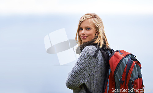 Image of Woman, hiking and portrait for travel, adventure and wellness on a cloudy sky or grey background in winter. Face of a young person in backpack for trekking, explore or journey outdoor with mockup