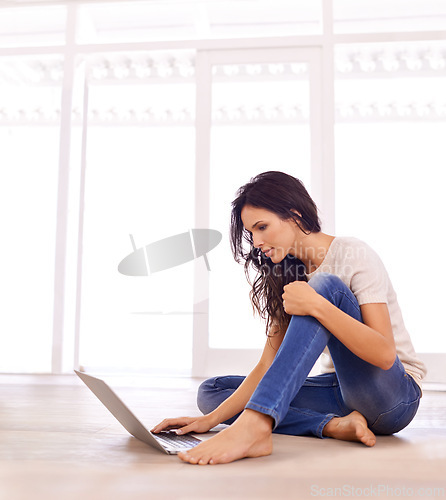 Image of Laptop, relax and serious with woman on floor of living room in home for email, internet or research. Computer, study and social media with confident young person in apartment for website browsing