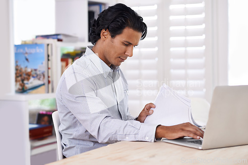 Image of Businessman, laptop and paperwork at desk in home for remote work, research or online planning in workspace. Financial analyst, person or technology with sales project, stock performance or documents