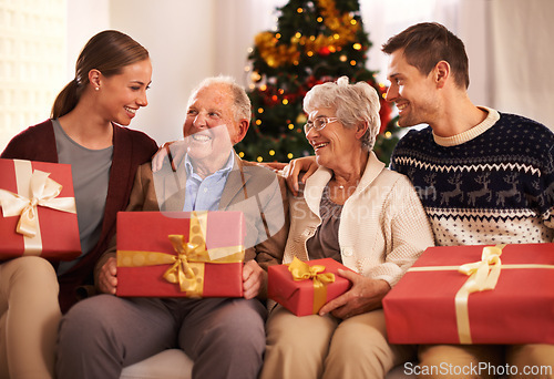 Image of People, grandparents and family with Christmas gift for festive season together for celebration, presents or holiday. Elderly man, woman and couch at home in Canada for bonding, vacation or relaxing